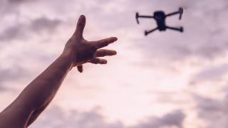 Best drones: Image shows woman holding out hand towards drone